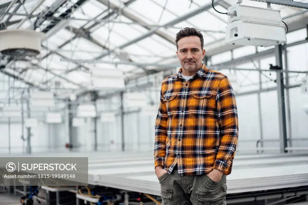 Businessman standing with hands in pockets at greenhouse