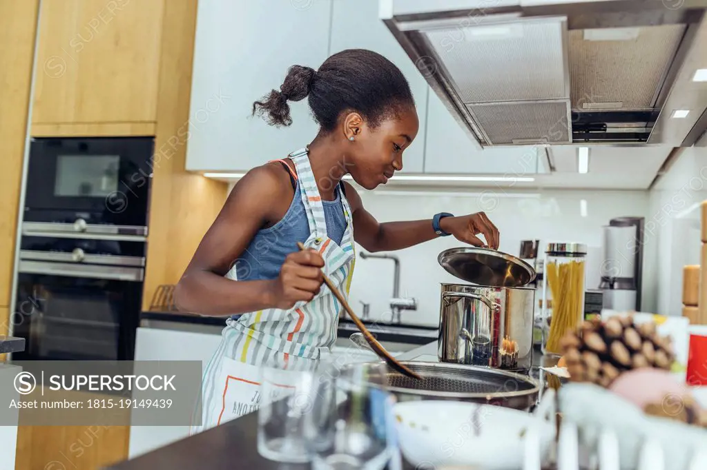 Pre-adolescent girl cooking food in kitchen