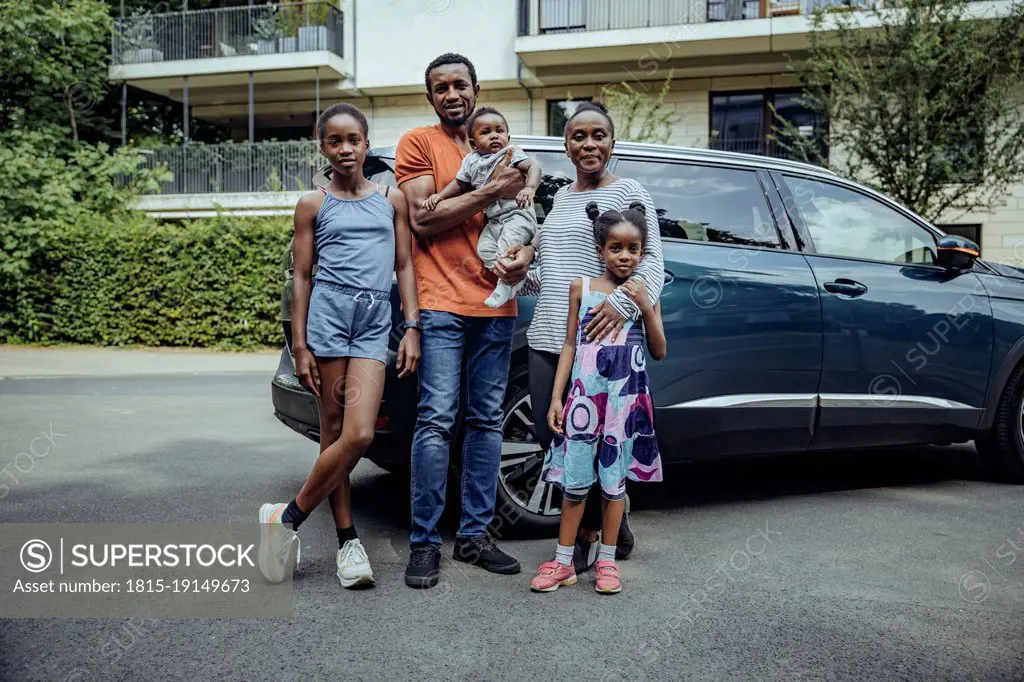 Family standing in front of car on road