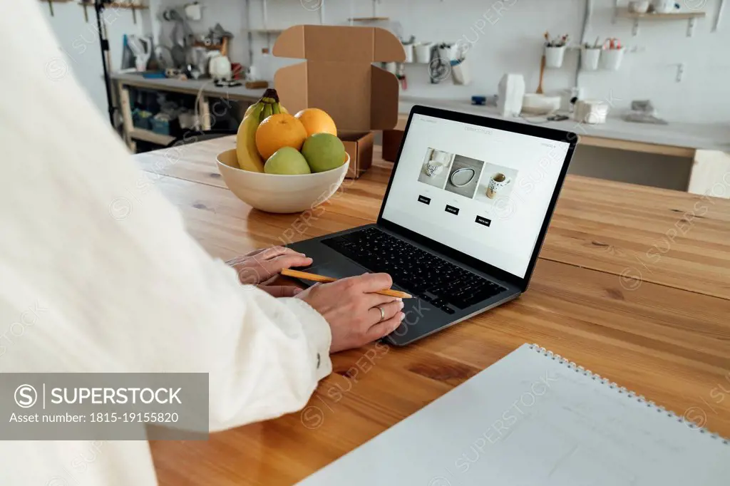 Entrepreneur examining her blog web page of ceramics on laptop in store