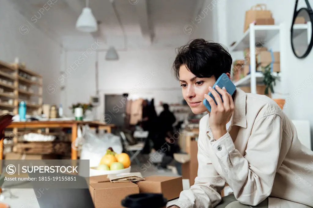 Owner talking on phone and working at ceramics workshop