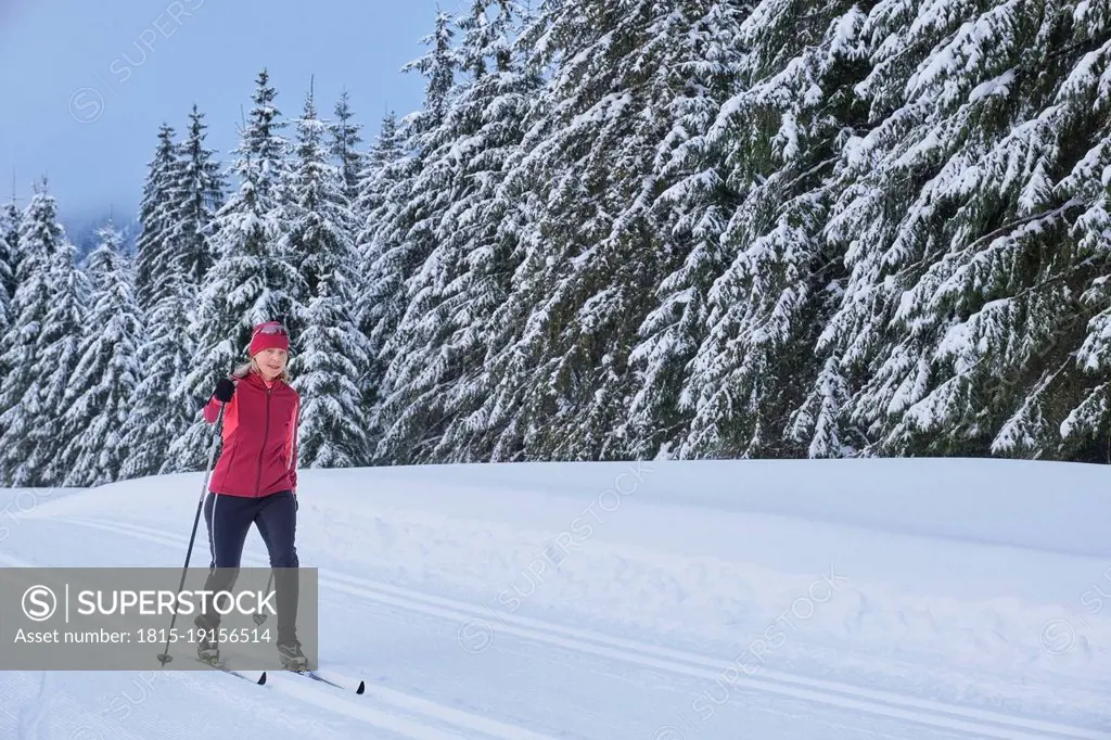 Senior woman skiing in winter forest