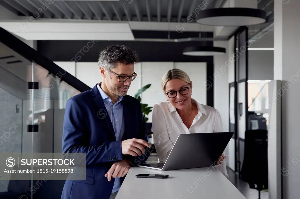 Business colleagues sharing laptop at office