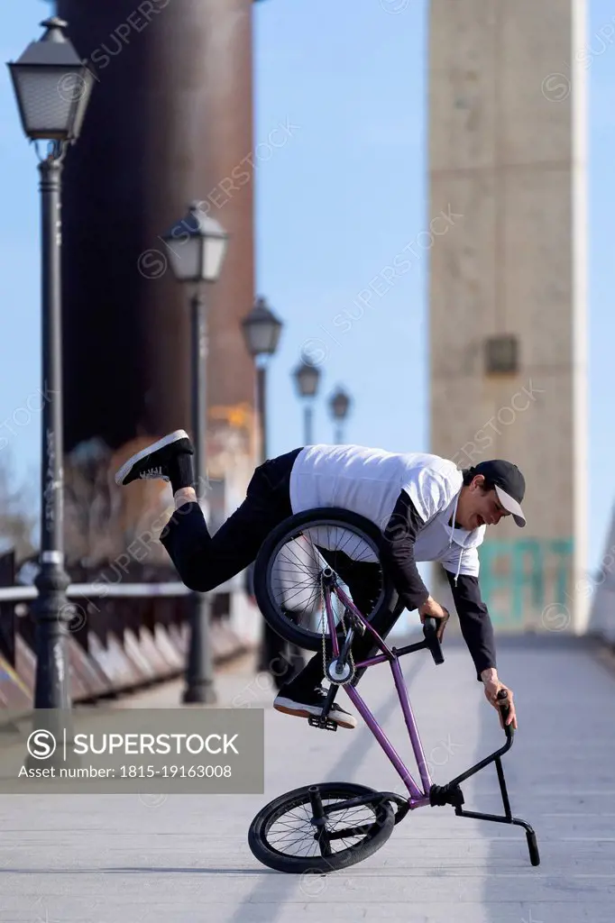 Man doing stunt with bicycle on street in city