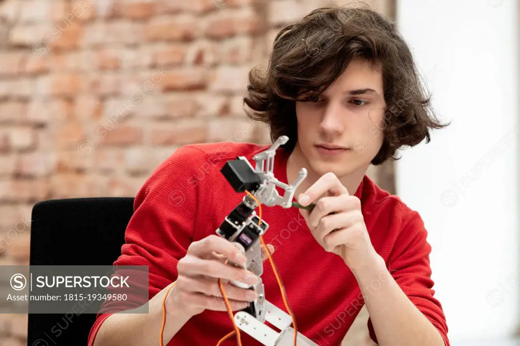 Teenage boy working on small robotic arm