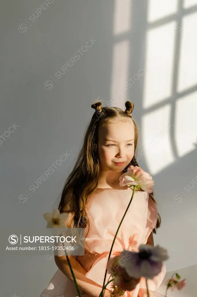 Girl with fresh flowers in front of white wall