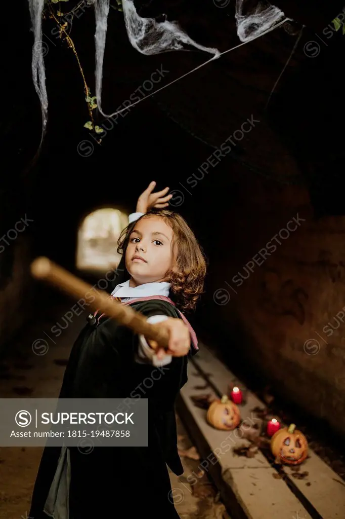 Girl wearing witch costume having fun in spooky tunnel at Halloween
