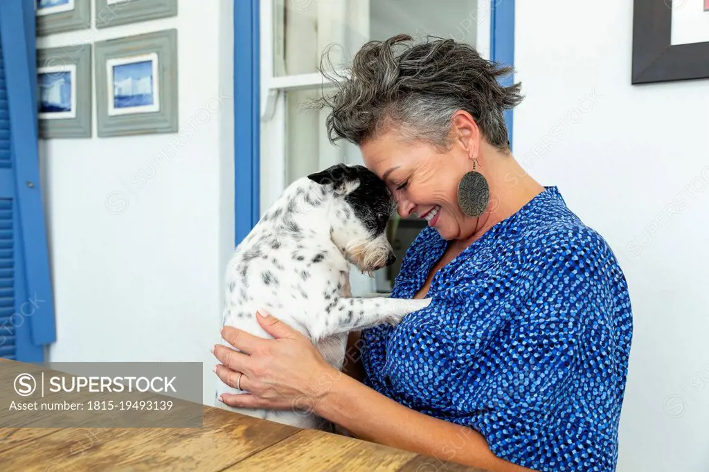 Happy woman embracing dog sitting at table