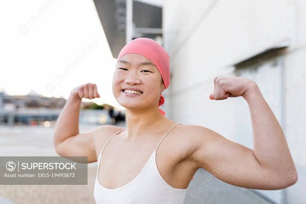 Happy woman wearing pink bandana showing biceps