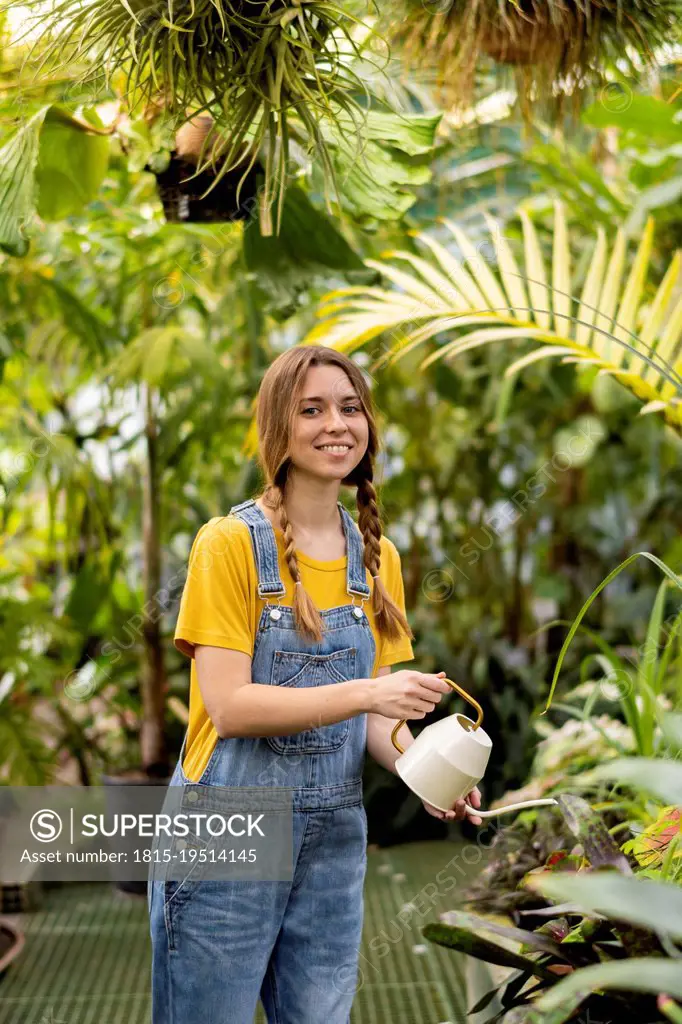 Happy woman watering plant in garden