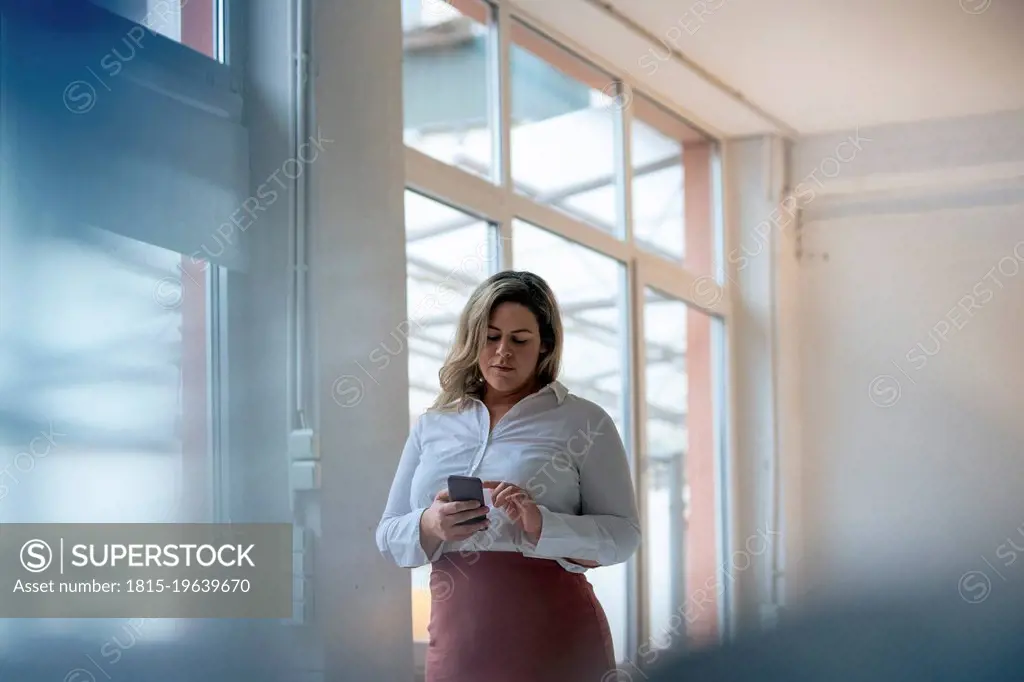 Businesswoman text messaging on smart phone at office