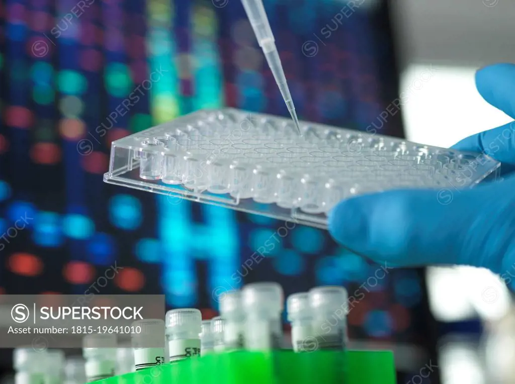 Scientist injecting sample in microtiter plate at laboratory