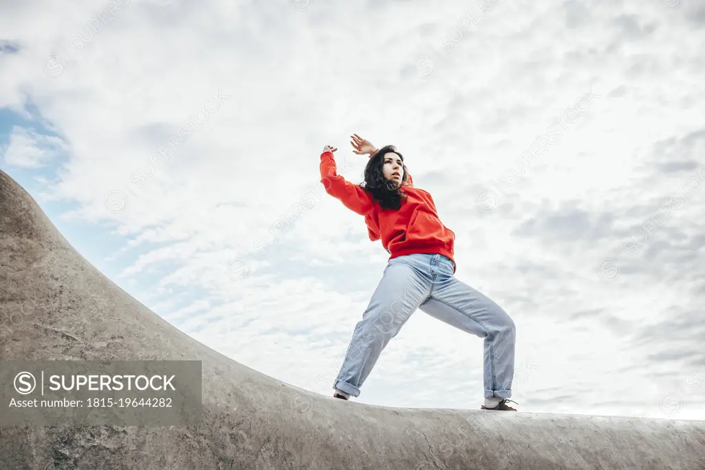 Woman with arms raised dancing under cloudy sky