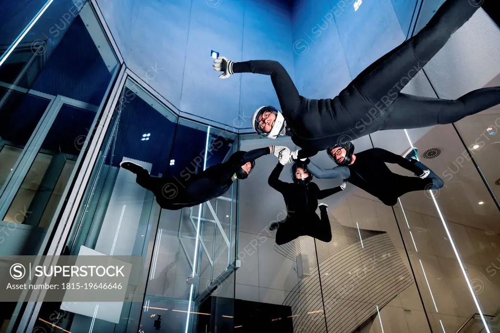 Athletes holding each others hands flying in wind tunnel