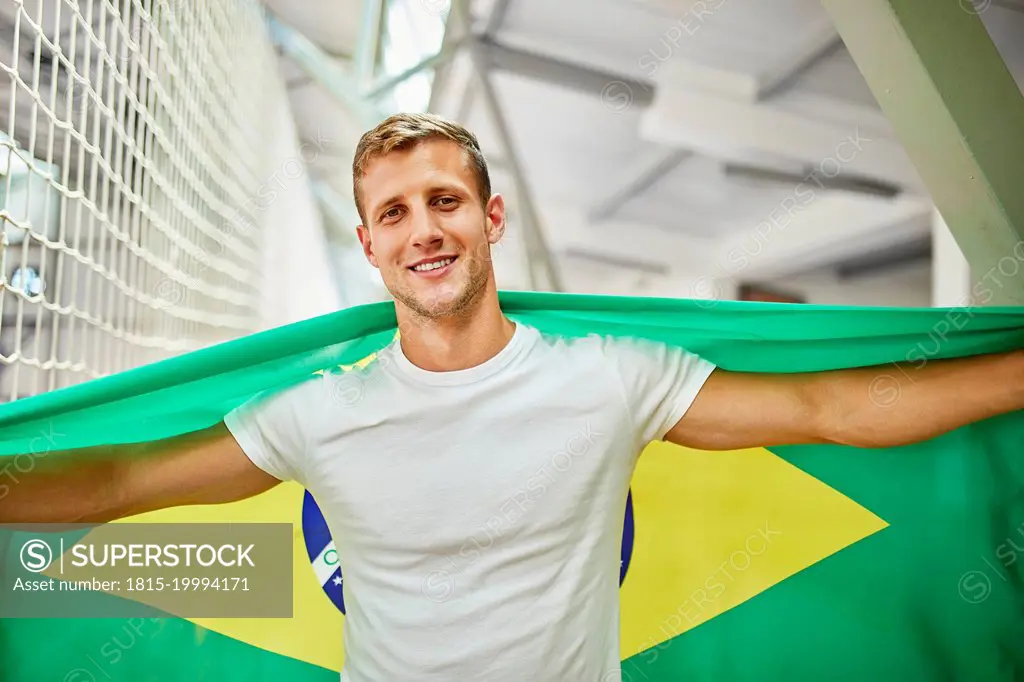 Smiling man holding Brazil Flag at sports event in stadium