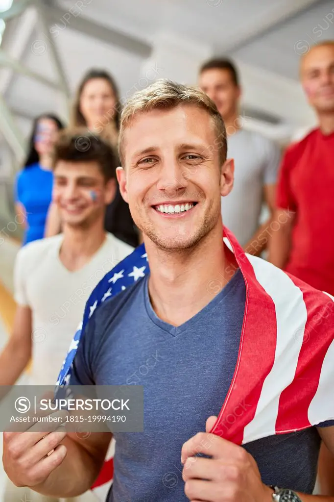 Smiling man holding American Flag in at sports event in stadium