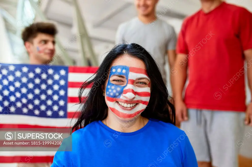 Smiling fan with American Flag face painted at sports event in stadium