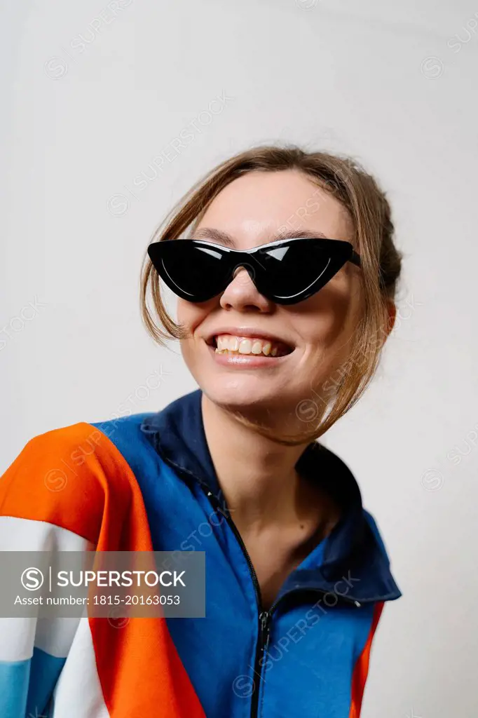 Smiling woman wearing sunglasses against white background