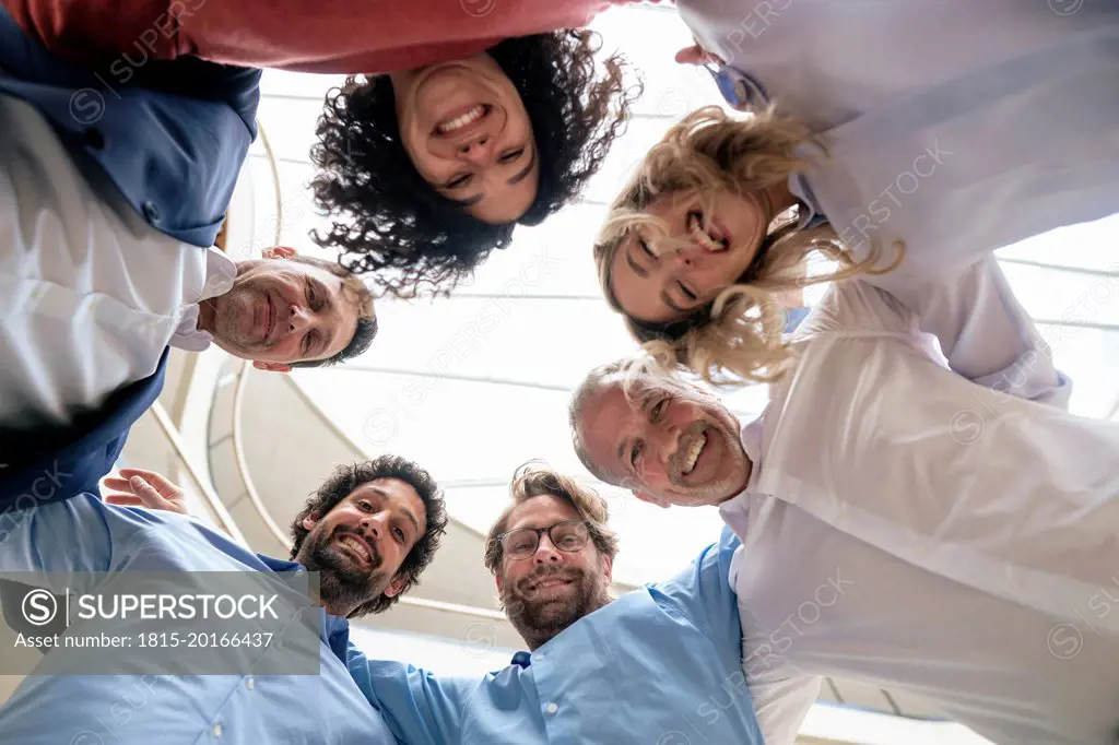 Cheerful multiracial business colleagues huddling at office