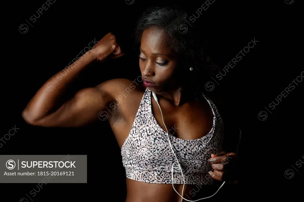 Muscular athlete flexing muscles against black background