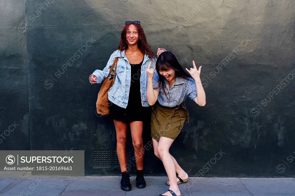 Happy friends having fun together standing in front of wall