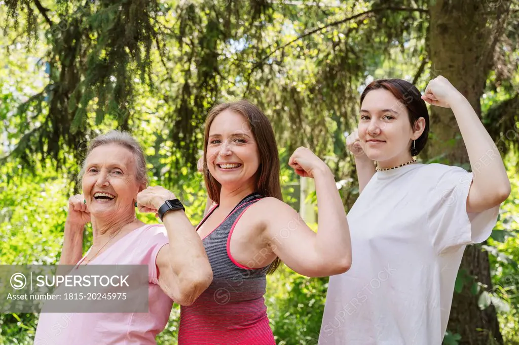 Active senior woman flexing muscles with daughter and granddaughter at park