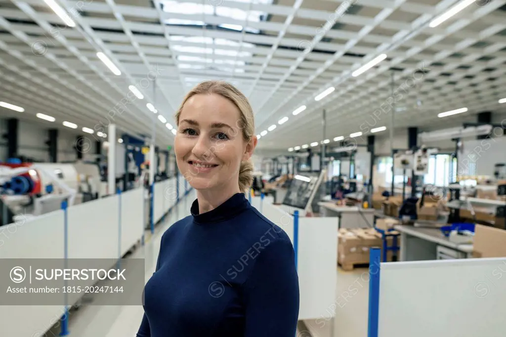 Smiling businesswoman with blond hair in factory