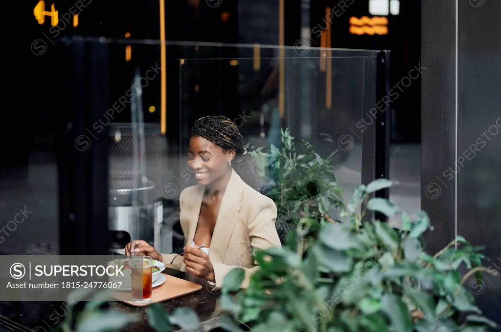 Happy businesswoman having food in cafeteria