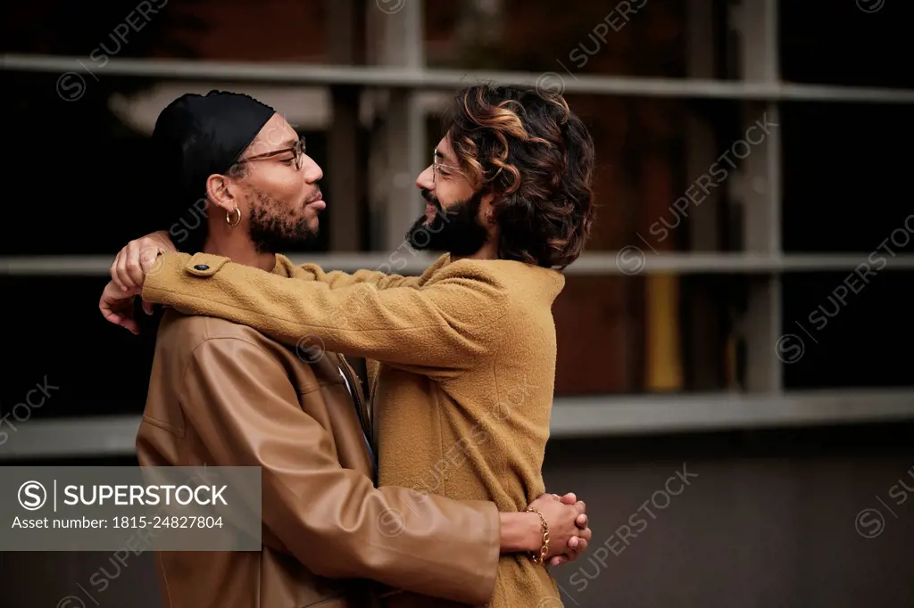 Smiling multiracial gay couple hugging each other