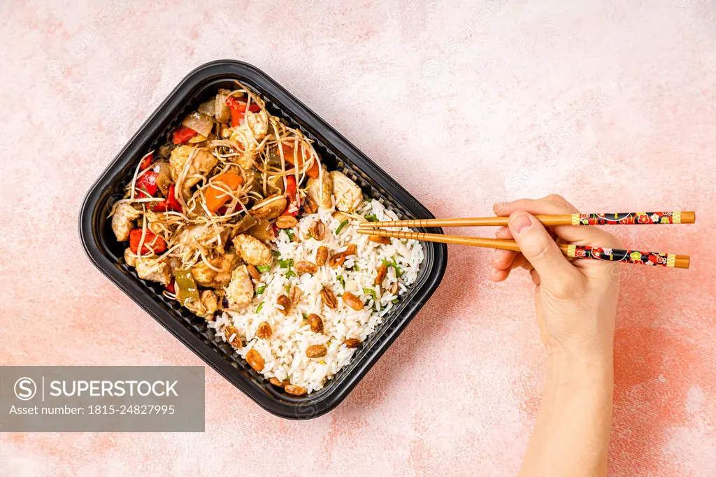 Personal perspective of woman eating take out chop suey