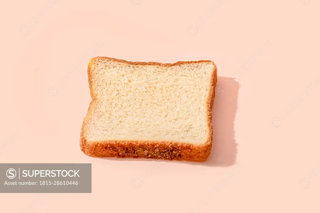 Slice of bread over peach background