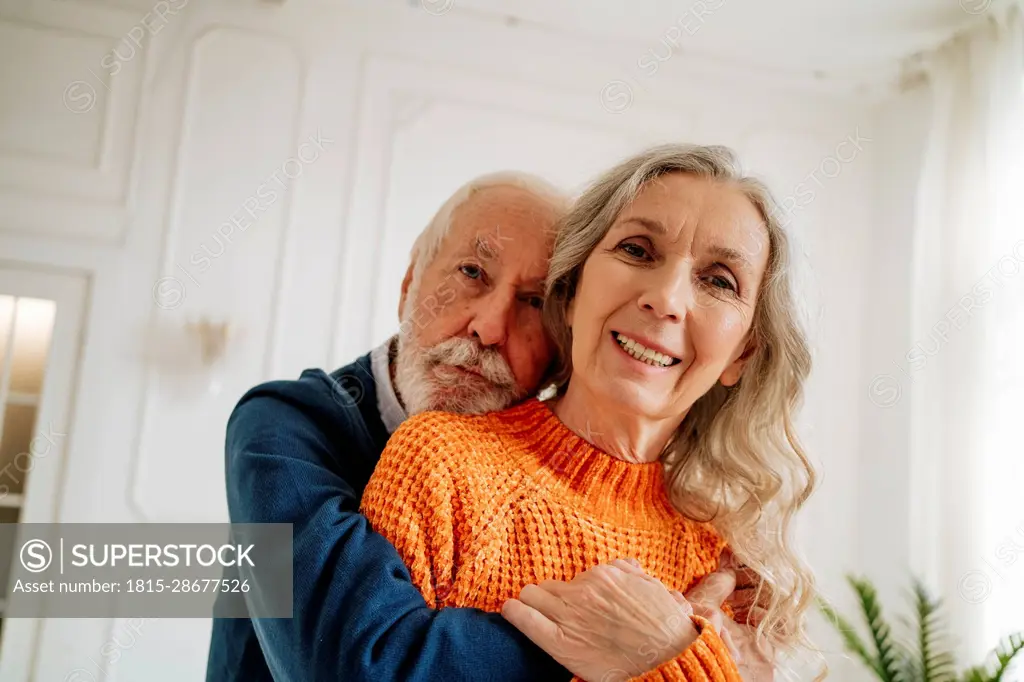 Loving senior couple embracing each other at home