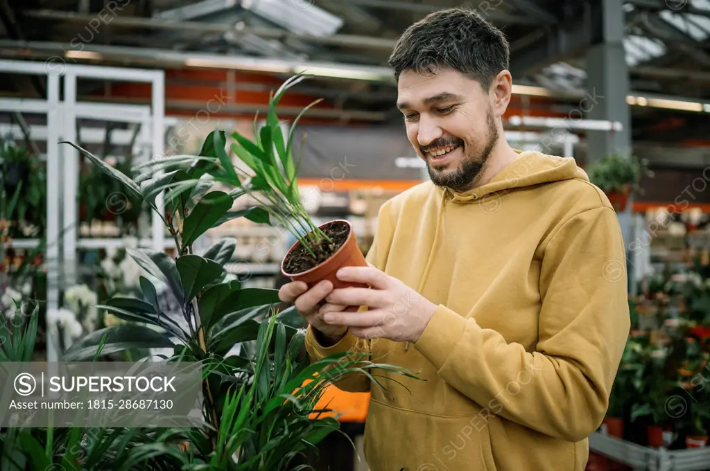 Happy man buying plant in garden center