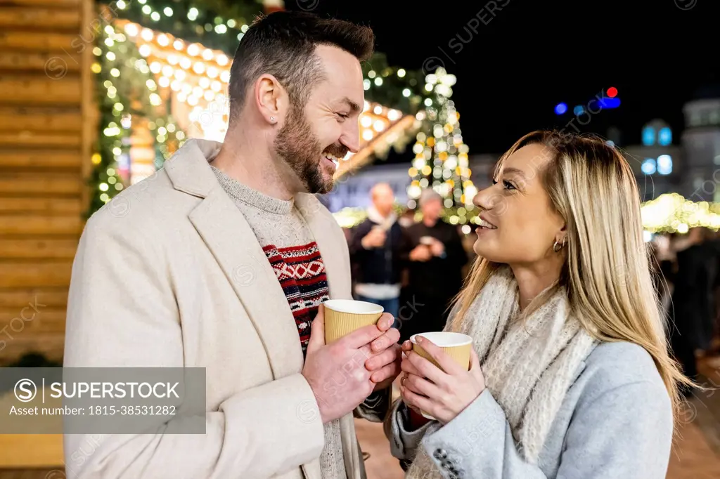 Happy man and woman with coffee cup at Christmas market