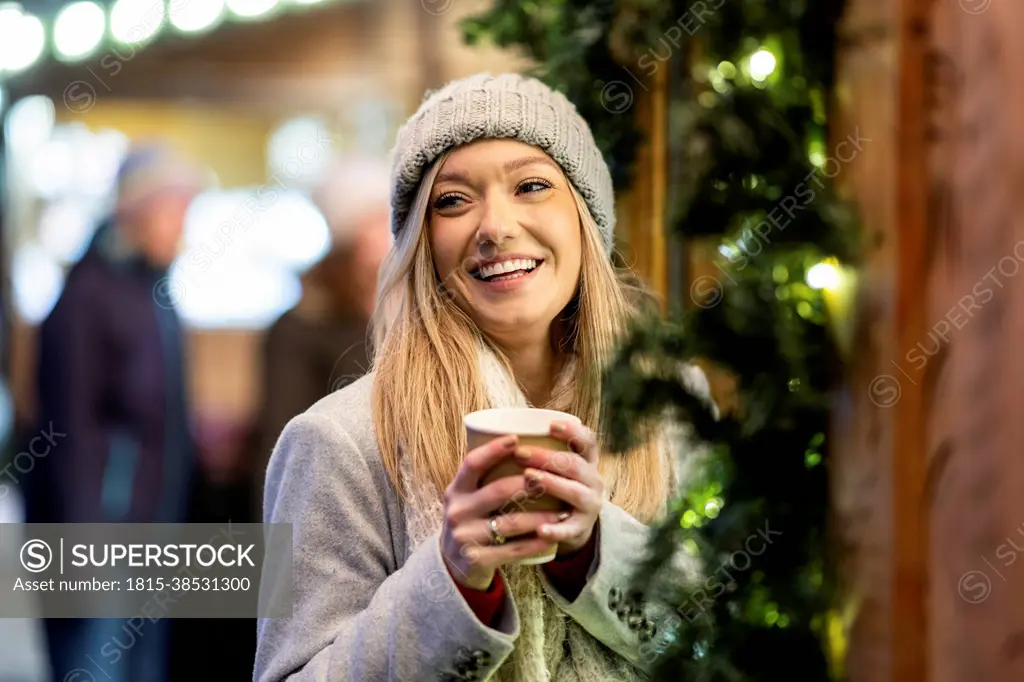 Happy young woman with coffee cup at Christmas market