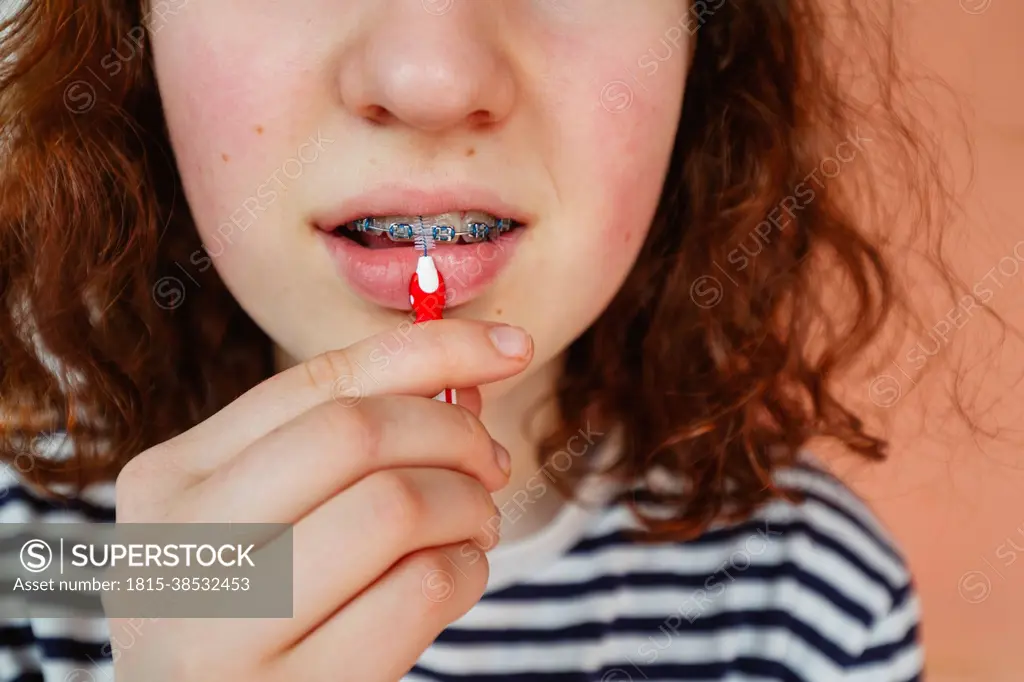 Girl cleaning dental braces with interdental brush