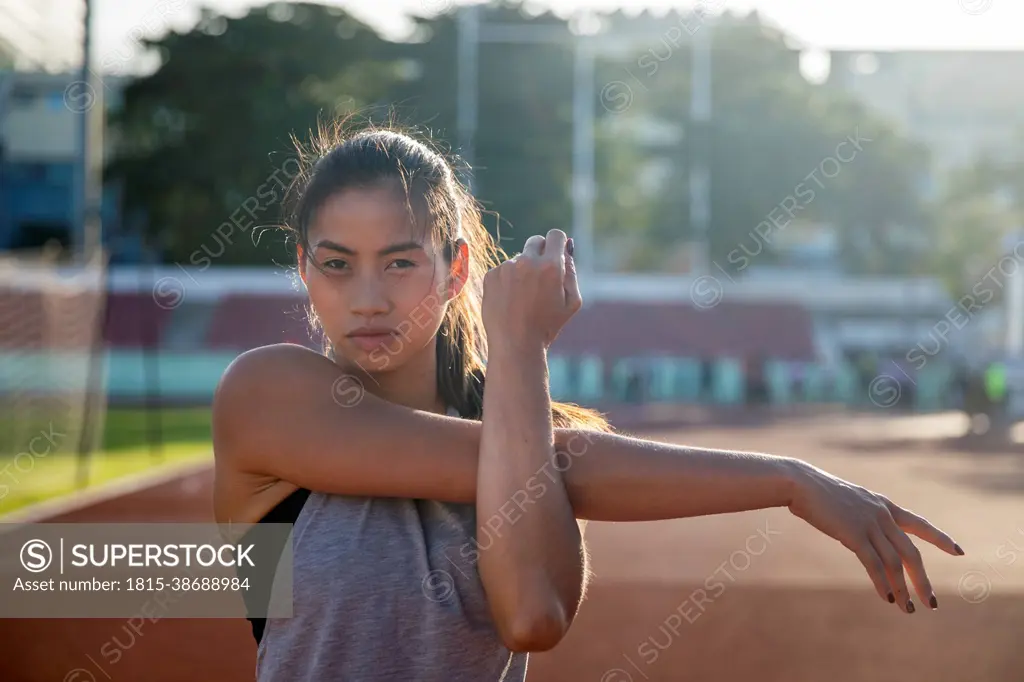 Young woman doing stretching exercise in sports field