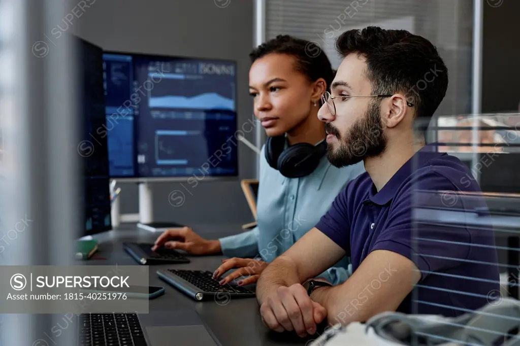 IT professionals working together on computers at desk