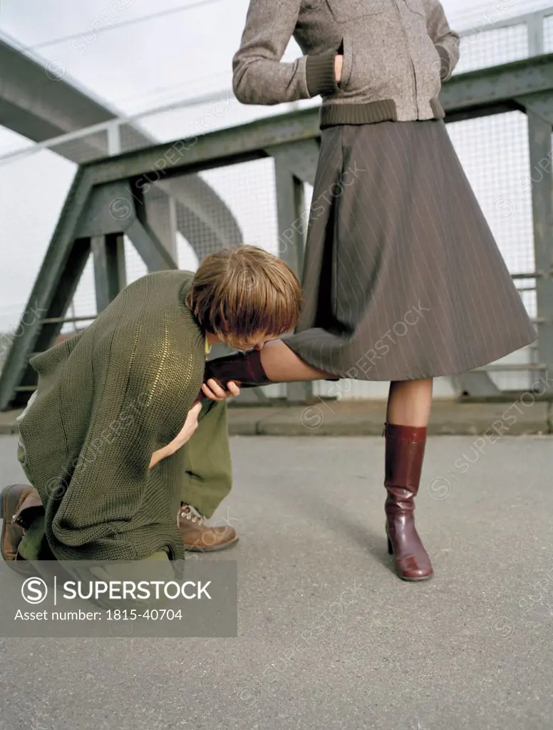 Kneeling man kissing foot of woman - SuperStock