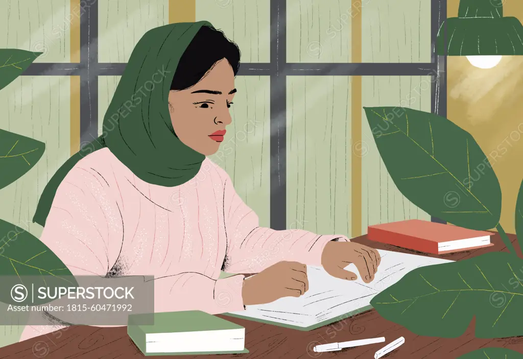 Woman wearing hijab reading book at home