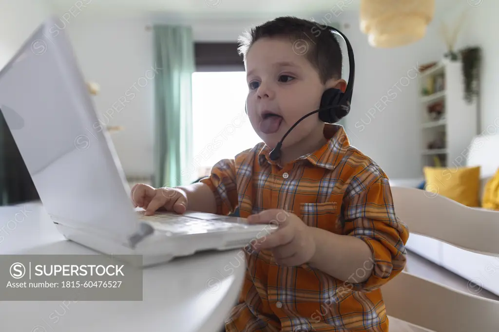 Boy wearing headset and using laptop at table