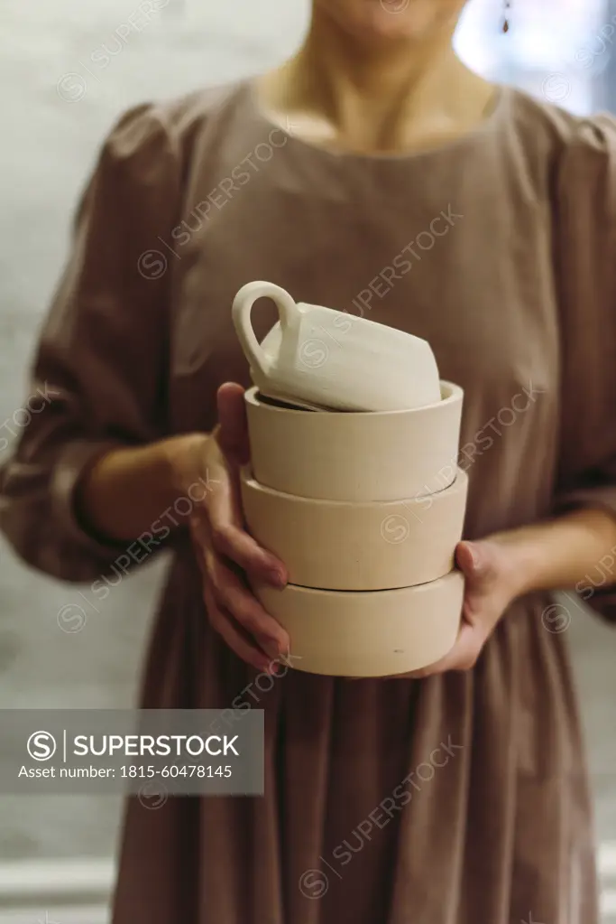 Potter holding handmade clay crockery in workshop