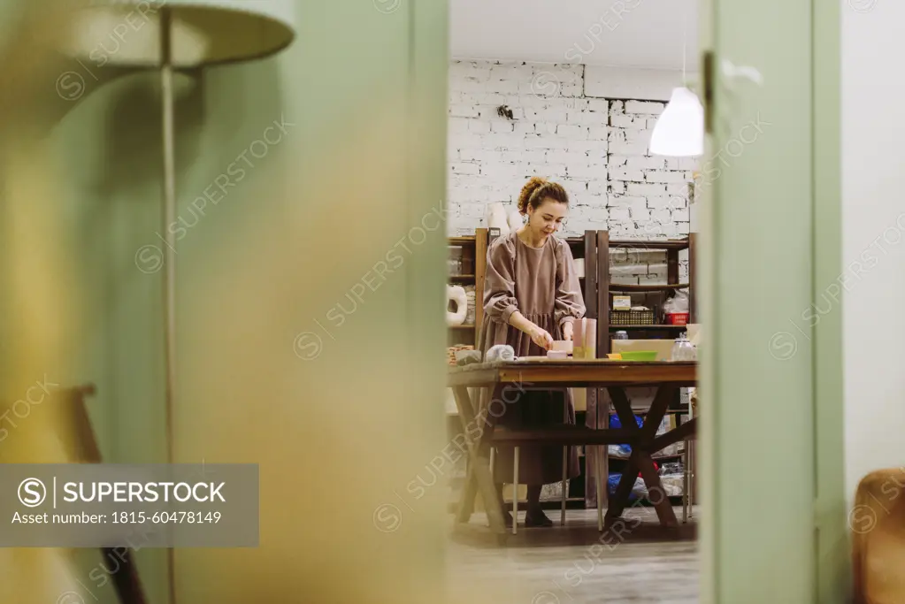 Reflection of businesswoman in mirror with crockery on desk at workshop