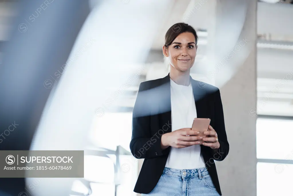 Confident businesswoman holding smart phone at office