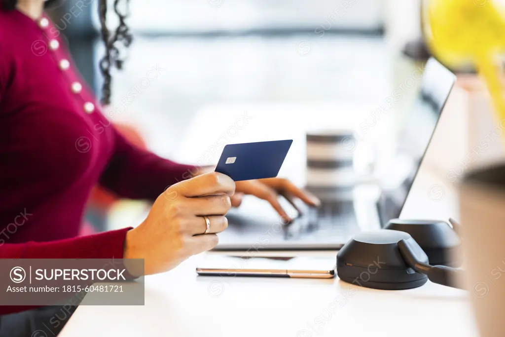 Businesswoman holding credit card and doing online shopping at office