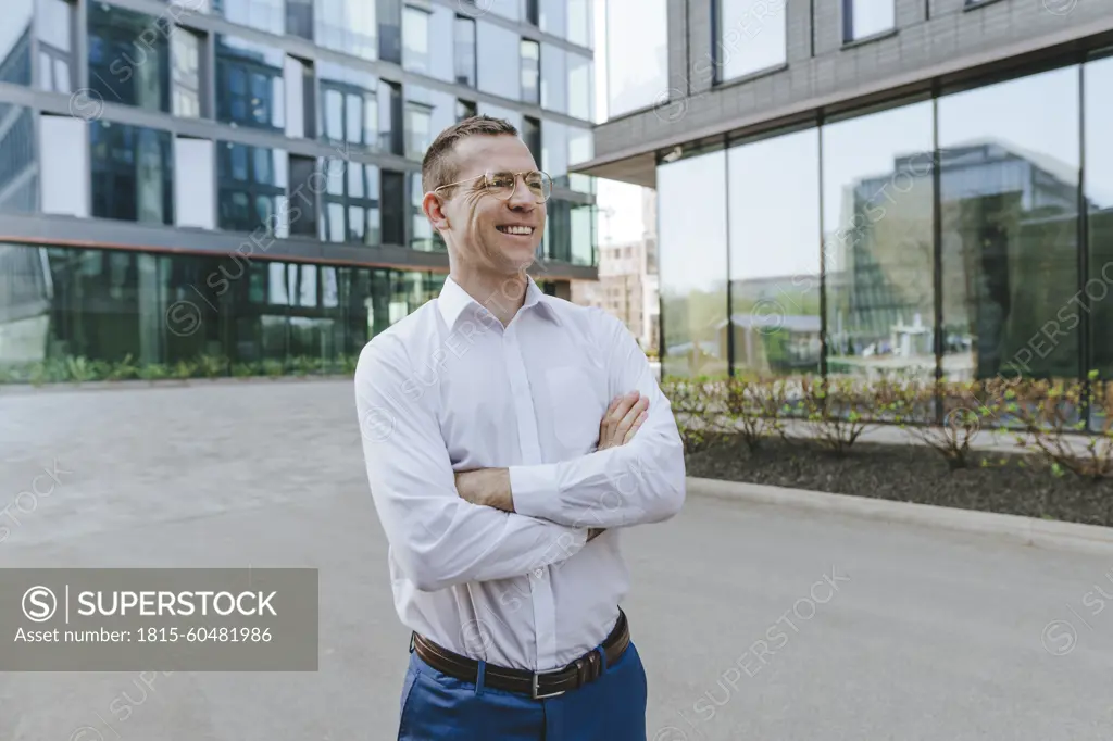 Confident businessman with arms crossed standing outside office building