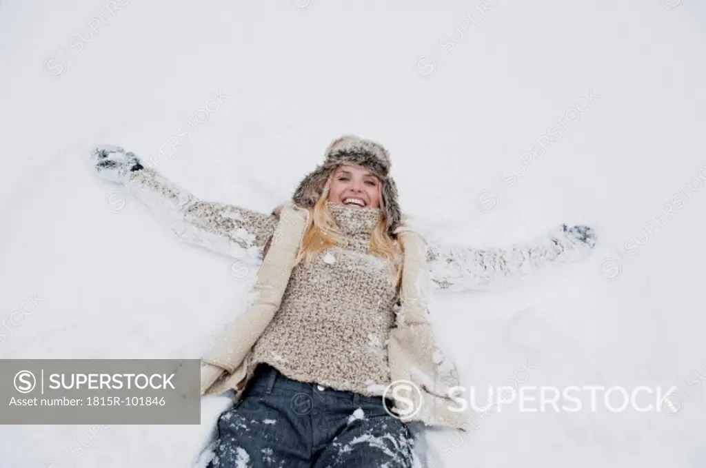 Austria, Salzburg County, Mid adult woman lying on snow, smiling