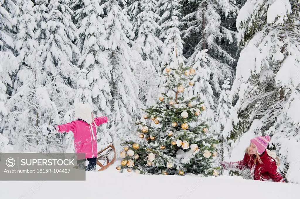 Austria, Salzburg County, Girls having fun in snow with christmas tree