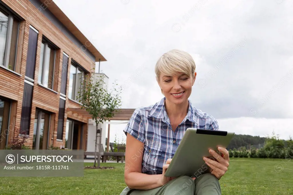 Germany, Bavaria, Nuremberg, Mature woman using digital tablet in garden