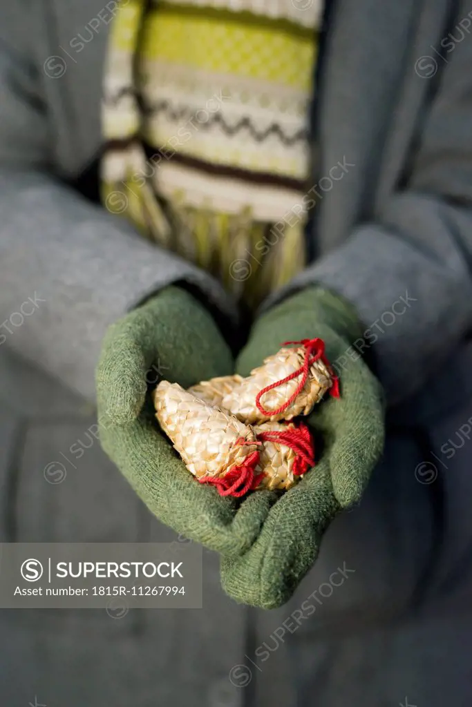 Young woman with gloves holding Christmas decoration, partial view